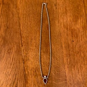 Silver necklace with teardrop pendant, pearl accent on top.